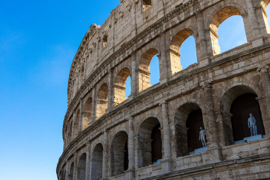 Famous Coliseum in Rome. Colosseum, or Coliseum. Part of the wall of an antique stone structure with arches. Italy, Europe. Famous touristic place in the world, Europe. Beautiful blue sky background.