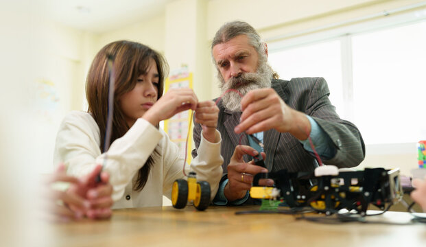 Teacher guides a student assembling a robotics project in a STEM classroom, encouraging engineering skills, problem solving, innovation, and hands-on learning.
