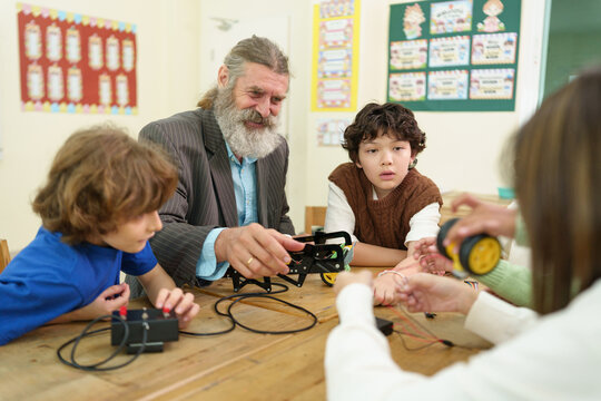 Teacher mentors students building a robotics project in a STEM classroom, encouraging engineering, coding, teamwork, and problem-solving through interactive hands-on learning.