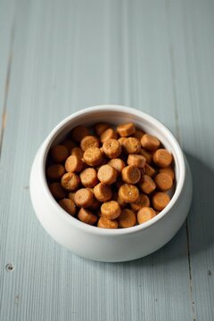 A bowl of round, golden-brown crunchy treats sits on a pale blue wooden surface