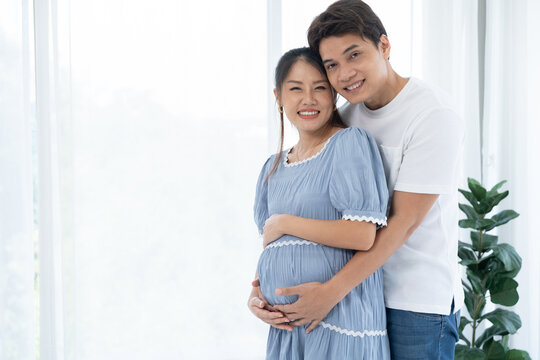 Couple preparing for baby together, husband caring for pregnant wife, symbolizing family bonding, maternity care, love, and wellness in cozy indoor environment with natural daylight and positive