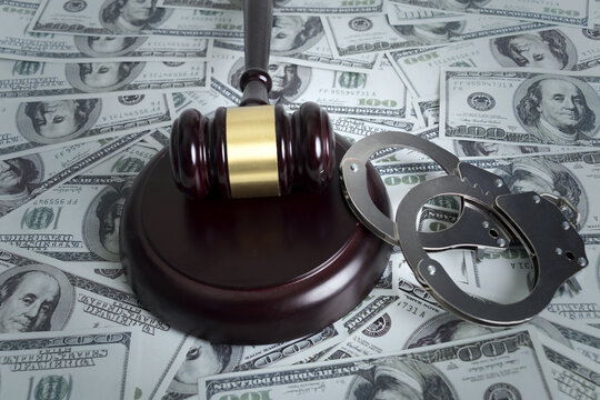 Gavel and handcuffs on US dollar banknotes symbolizing corruption and financial crime