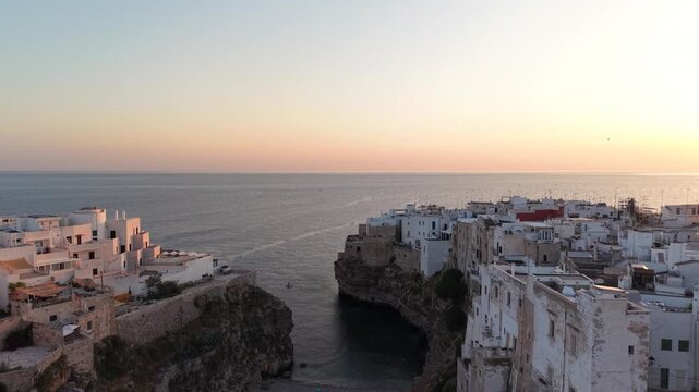 Spectacular sunset over the iconic coastal town of polignano a mare, italy, with historic white buildings perched on limestone cliffs overlooking the adriatic sea