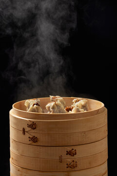 Steaming siu mai dumplings in bamboo steamer on black background