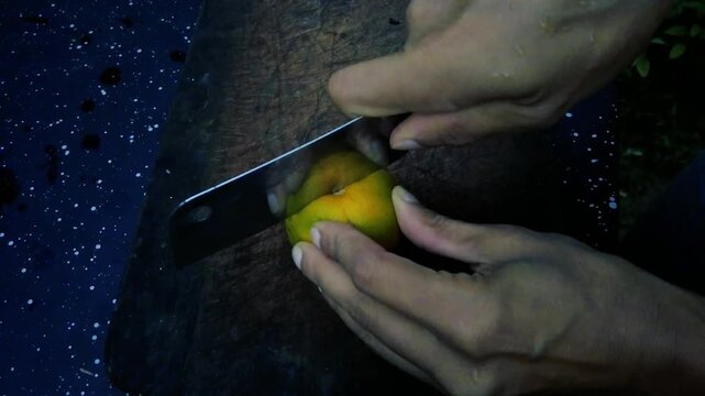 Person slicing fresh yellow citrus fruit on wooden cutting board with sharp knife