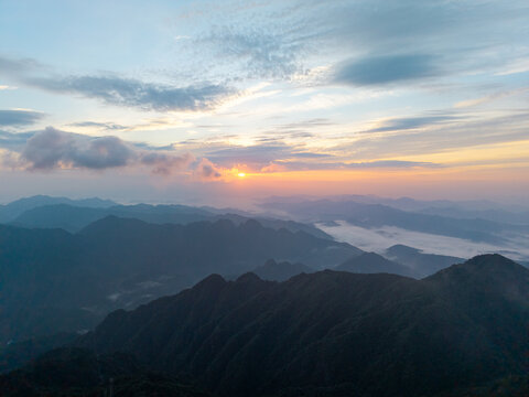 The sun rises over the majestic peaks and rolling clouds of Sanqingshan Mountain located in the Jiangxi province of China during a beautiful clear morning
