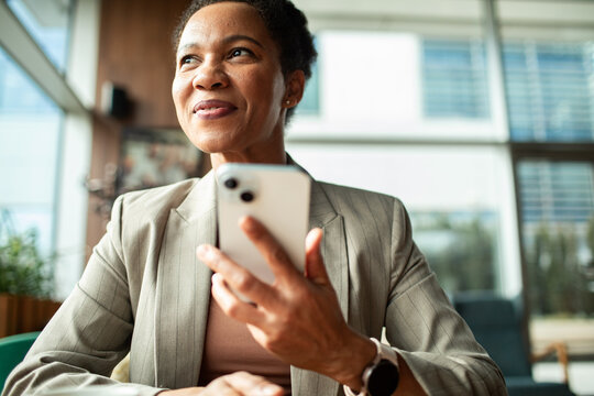 Confident businesswoman using smartphone in office