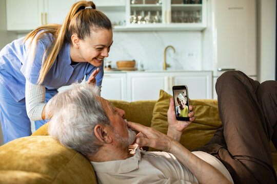 Caregiver helping senior man on video call at home