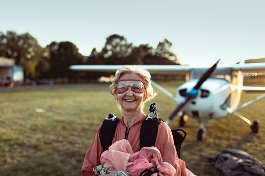 Smiling senior woman skydiver holding parachute at airfield