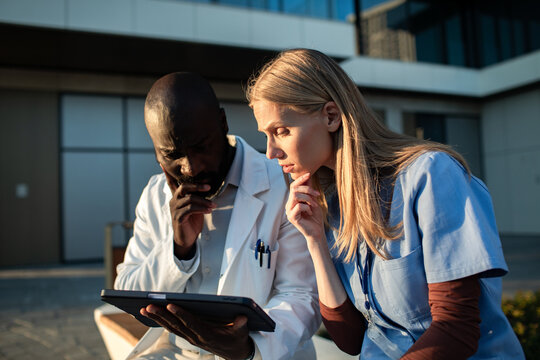 Doctors reviewing patient data on tablet outside hospital