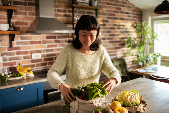 Woman unpacking fresh vegetables in home kitchen