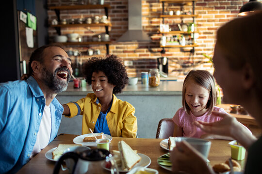 Happy family laughing at breakfast in kitchen