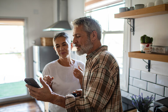 Senior couple using smartphone in home kitchen