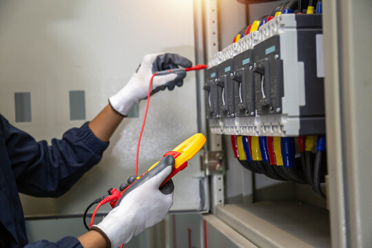 Checking the electrical system, an electrician is using an electric meter to check the electrical system at a control cabinet. for safety