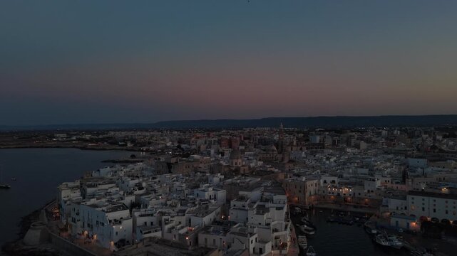 Breathtaking aerial view of monopoli's historic old town at dusk, with the enchanting harbor, ancient cathedral, and stunning coastline in apulia, italy