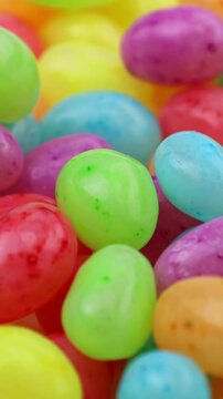 Many colorful fruit jelly beans falling down close up, vertical video