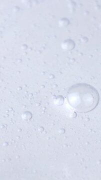 Transparent cosmetic liquid gel with bubbles flowing close up, vertical video format