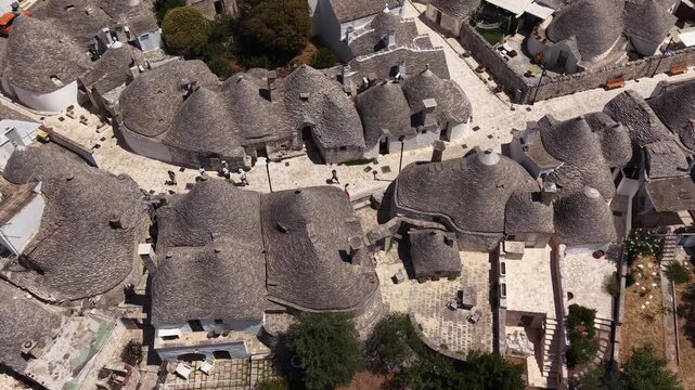 Aerial top-down view of alberobello's historic trulli houses, a unesco world heritage site, with tourists exploring the ancient limestone dwellings in puglia, italy