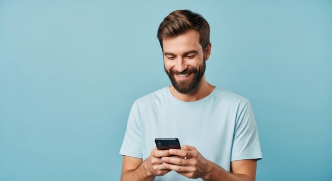 Happy Young Man Smiling While Using Smartphone Over Blue Background with Copy Space