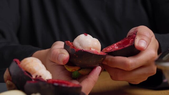 Hands squeezing open a Mangosteen, tropical and exotic fruit