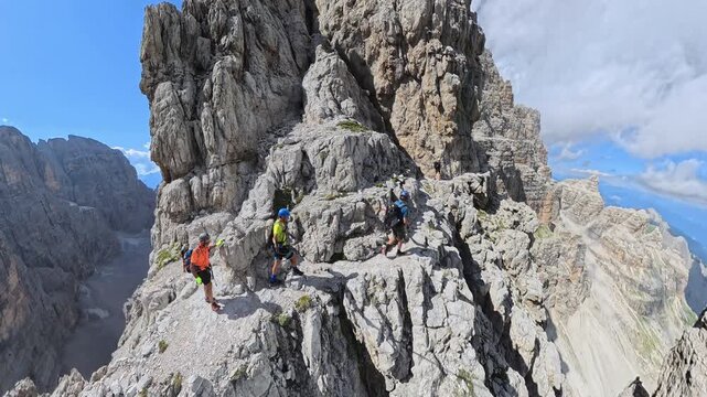 Three Hikers Crossing Via Ferrata Bocchette Centrali Below Campanile Alto in the Brenta Dolomites