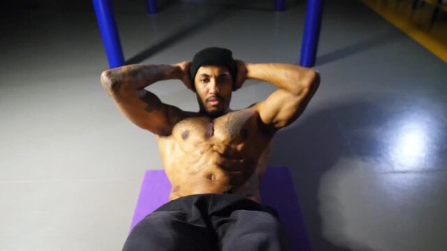 Afro american sportsman training abdominal muscles on fitness mat at gym. Muscular african athlete working out at sport club. Strong black guy exercising indoor. Concept of healthy active lifestyle