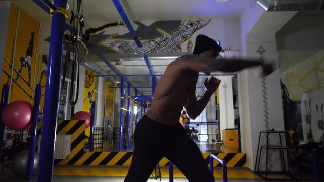 Muscular african boxer demonstrating punches at sport club. Young afro american sportsman practicing shadow boxing at modern gym. Strong black kickboxer training indoor. Healthy lifestyle concept