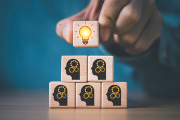 Businessman hand putting glowing lightbulb on human brainstorming which print screen on wooden block for creative thinking idea and innovation to problem solving concept. © Dilok