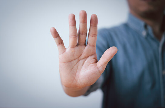 Stop gesture with an open hand signaling protection, rejection and personal boundaries. Business concept representing safety, prevention, refusal, awareness and human rights with copy space.