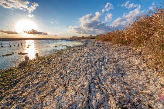 Beautiful sunset landscape over a lake shore with cracked dry mud and sunbeams
