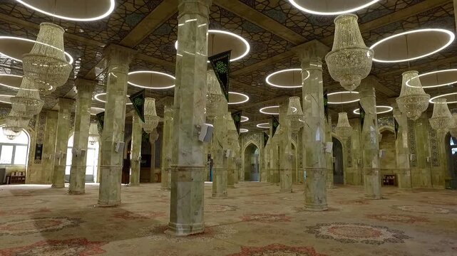 Tall columns and arches inside historic mosque under soft light showing Islamic architecture and ornate interior details.
