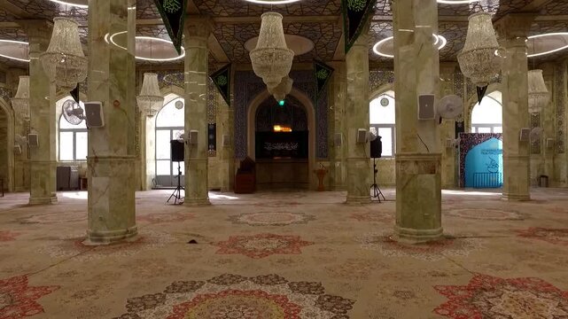Ornate chandelier and columns inside historic mosque under soft light showing Islamic architecture and decorative interior.