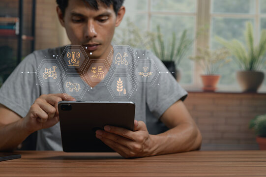 Young man using tablet with digital technology icons in bright modern home