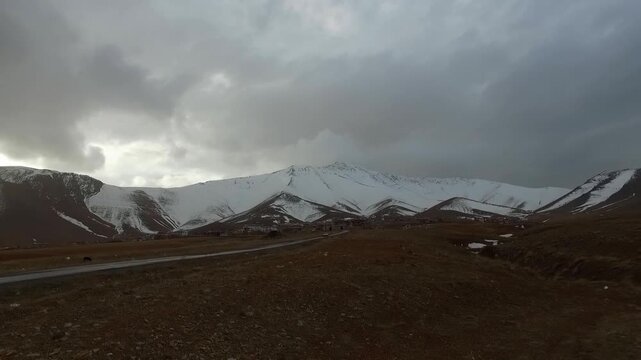 Snow covered mountain range under cloudy sky in winter landscape during daytime showing white peaks and open terrain.