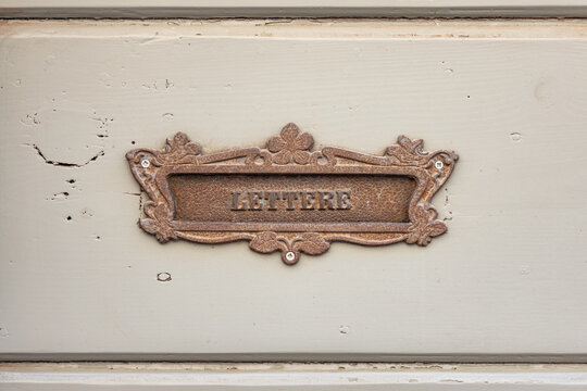 Vintage decorative mailbox slot with the Italian word "LETTERE" on an old wooden door, symbolizing traditional mail, correspondence, communication, and nostalgia.