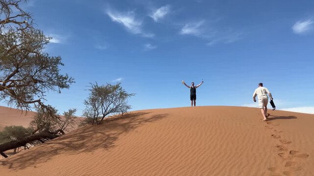 Two male adult adventurers climbing dune in Sossusvlei, Namibia Africa