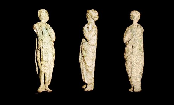 Ancient Roman pocket god figurine of Cora, bronze travel idol of a roman legionary with green patina, isolated on black.