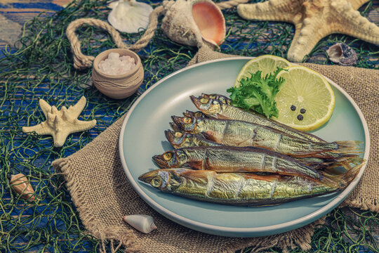 Smoked smelt with fresh lemon and herbs. Salted fish with marine decor. Trendy dish, sea rope