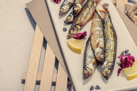 Smoked smelt with fresh lemon and herbs. Salted fish with marine decor. Trendy dish, sea rope