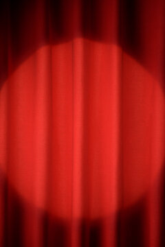 Red curtain with a bright spotlight shining on stage.
