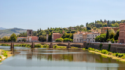 Obraz premium Arno river in Florence. Wide scenic view of bridge and waterfront buildings reflecting on water.