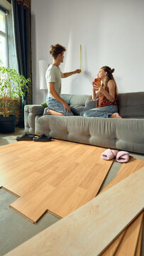 Young couple measuring wall while planning furniture placement. Concept of space planning and coordinated renovation in furniture retail, home improvement and relocation campaigns.