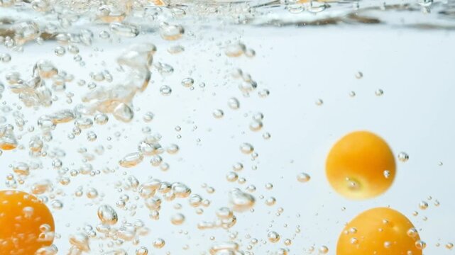 Slow motion shot of physalis fruits submerging into clean water with air bubbles