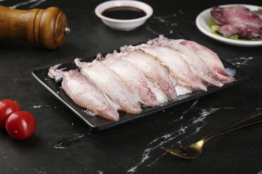 Fresh Raw Squid Slices on Black Plate with Soy Sauce for Asian Cooking
