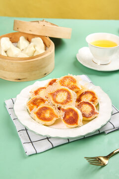 Chinese Pan-Fried Dumplings with Crispy Golden Bottom and Traditional Tea Setting