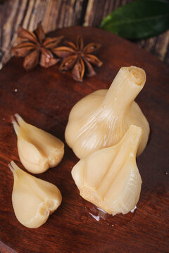 Fresh Peeled Garlic Bulb and Cloves with Star Anise on Wooden Cutting Board