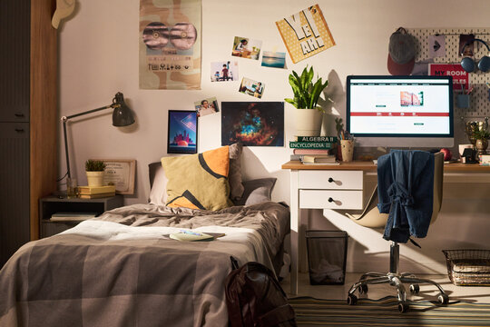 Wide angle view of teenager bedroom showing study desk, computer, textbooks, bed, reflecting student learning routine and home organization. Ideal for education, youth lifestyle, dorm marketing