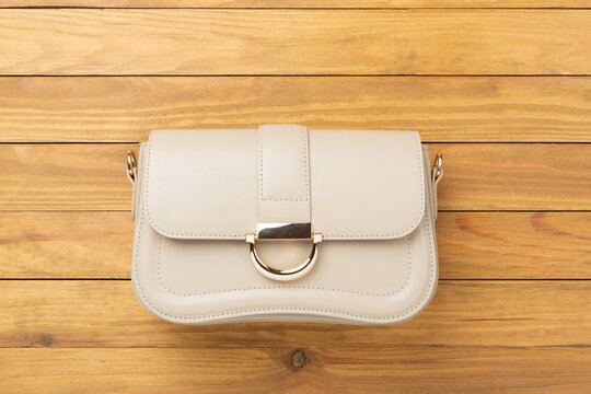 Woman leather bag on wooden background, top view