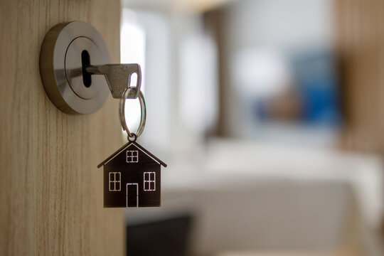 Open door to a new home with key and home shaped keychain. Mortgage, investment, real estate, property and new home concept