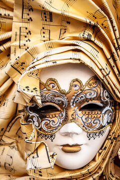 Venetian music note mask. Traditional white face mask wrapped in sheet musical paper headpiece detail.